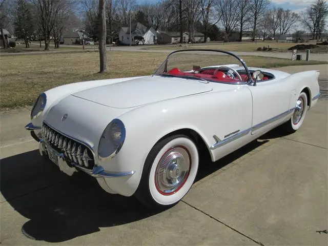 1417819-1953-chevrolet-corvette-thumb - Engine Stories Classic white convertible car with red interior parked outdoors, perfect for vintage enthusiasts and automotive collectors.