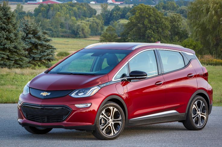 Red electric car parked on a scenic country road, showcasing sleek design and modern technology.