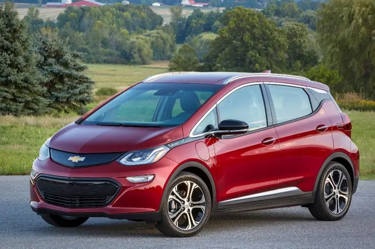 2019 Chevrolet Bolt EV Lights Up Safety Chart _ Cars_com - Engine Stories Red electric car parked on a scenic country road, showcasing sleek design and modern technology.