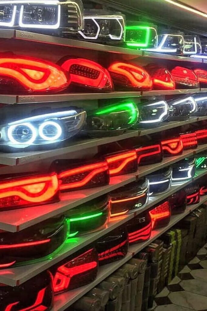 Rows of colorful car headlamps and taillights displayed on shelves in a store, showcasing various styles and colors.