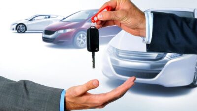 Handing over car keys with cars in the background, symbolizing car purchase or rental.