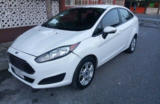 White Ford Fiesta parked on a residential street, side view.