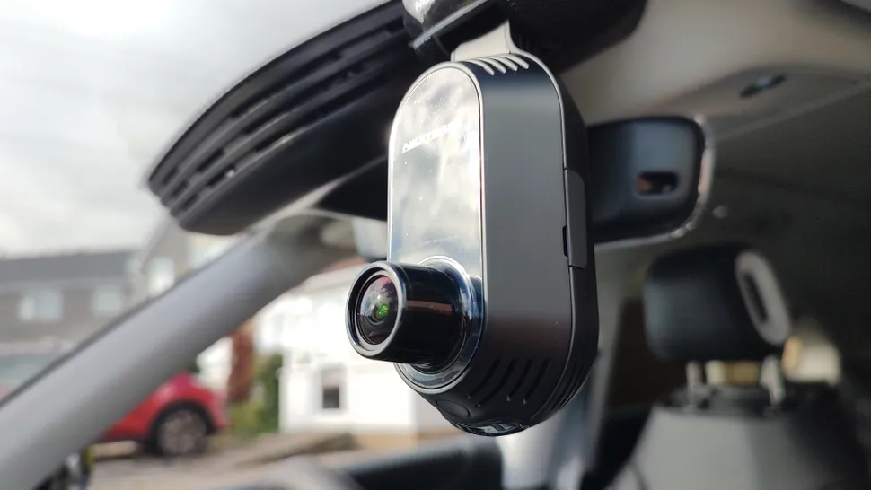 Car dash cam installed on windshield for recording and safety. Compact design with front view lens.