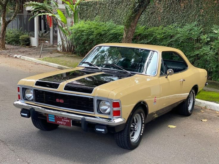 Vintage tan and black muscle car parked on a leafy street, showcasing classic SS design and styling.