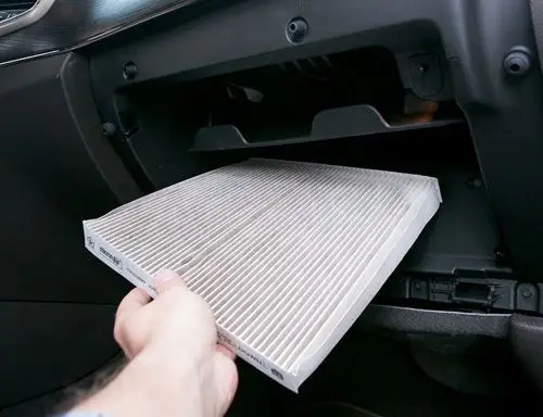 Whats a Cabin Air Filter and When Should You Replace It_ _ Cars_com - Engine Stories Hand replacing a car cabin air filter inside the glove box.