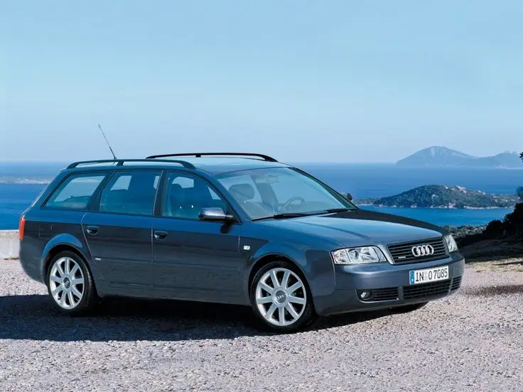 Wheelsage - Engine Stories Blue Audi A6 Avant with ocean view background, parked on a scenic cliffside road, highlighting sleek design and style.