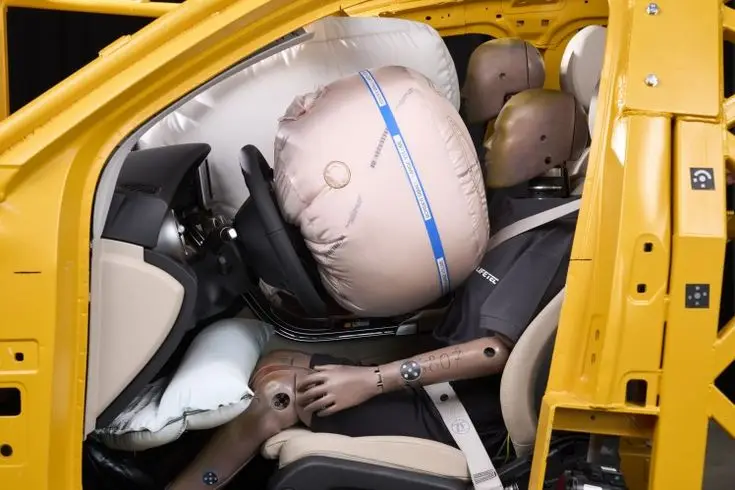 ZF LIFETEC Innovates Dual Contour Airbag for Enhanced Safety in Automated Driving - Engine Stories Crash test dummy in a yellow vehicle with airbags deployed, demonstrating safety features and passenger protection.