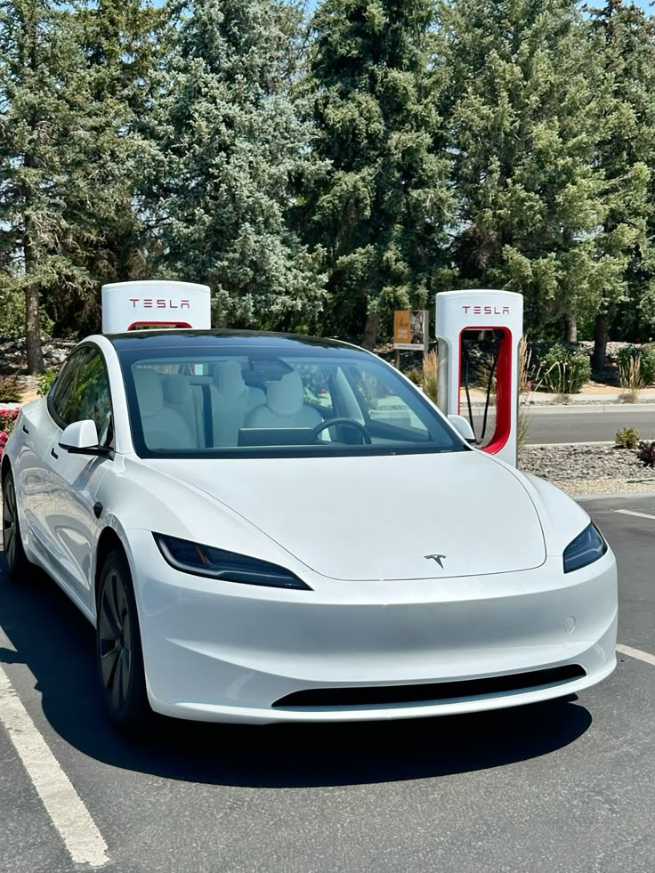 White Tesla Model 3 at a charging station amid trees, highlighting eco-friendly electric vehicle technology and sustainability.