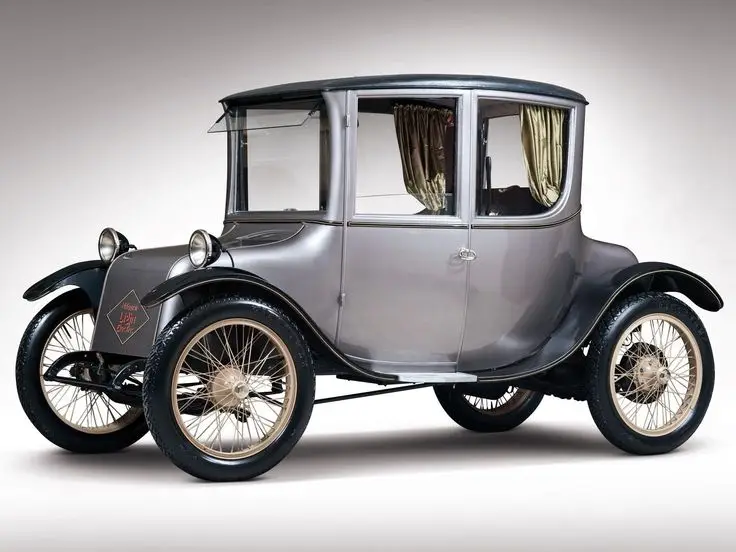 Vintage grey electric car with a classic design and spoked wheels, highlighting early 20th century automotive innovation.