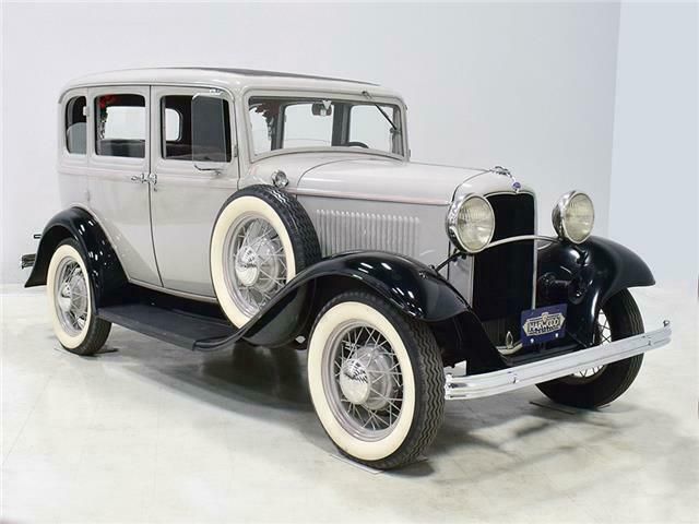 1932 Ford Model B 66312 Miles Gray 4-door 201 cubic inch inline-4 Manual for sale - Engine Stories Vintage 1930s car, silver and black, classic design with whitewall tires. Retro automotive elegance on display in a bright setting.