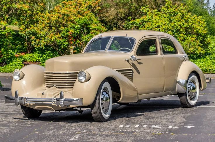 Vintage beige classic car parked outdoors, showcasing elegant design and sleek curves in a sunny setting.