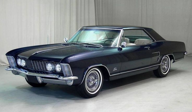 1963 Buick Riviera - Engine Stories Classic vintage car in a showroom, featuring sleek design and chrome accents, showcasing automotive elegance and style.