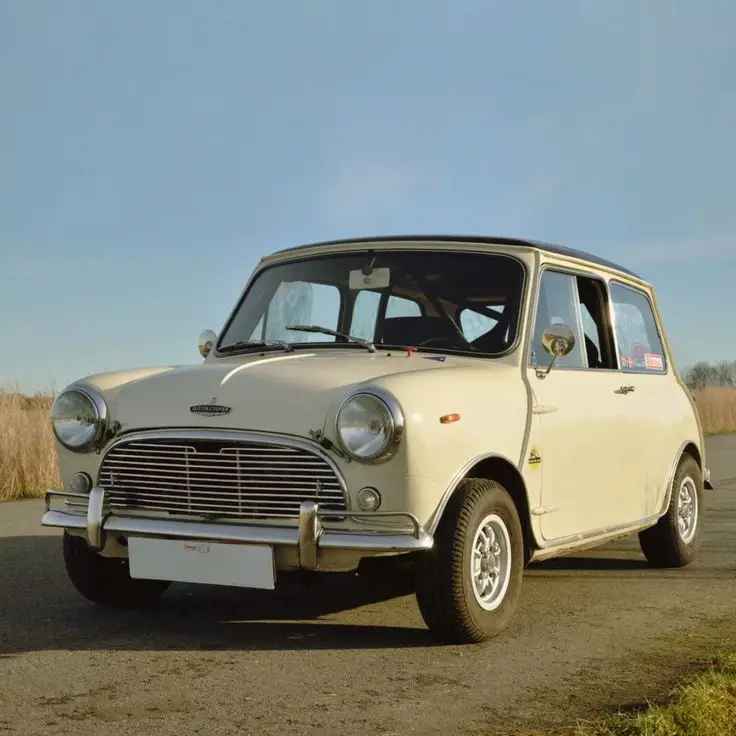 1964 _ Austin Mini Cooper S 1275 - Engine Stories Classic white vintage car on a sunny day, parked on a rural road, showcasing its iconic design and timeless appeal.