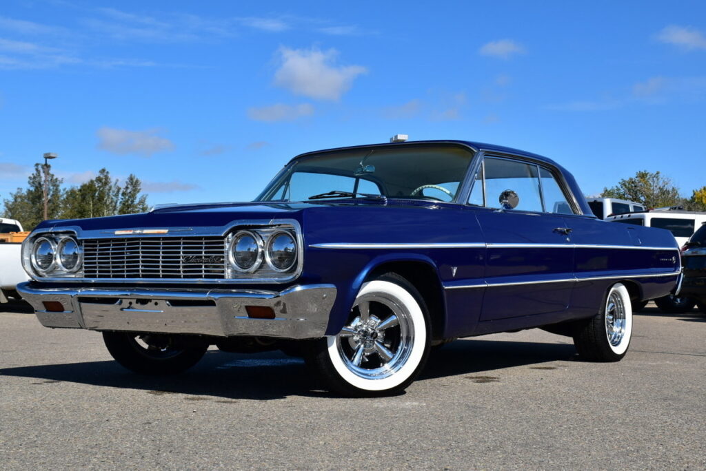 1964 chevrolet impala lowrider - Engine Stories Classic blue 1964 Chevrolet Impala against a clear sky, showcasing vintage style and polished chrome details.