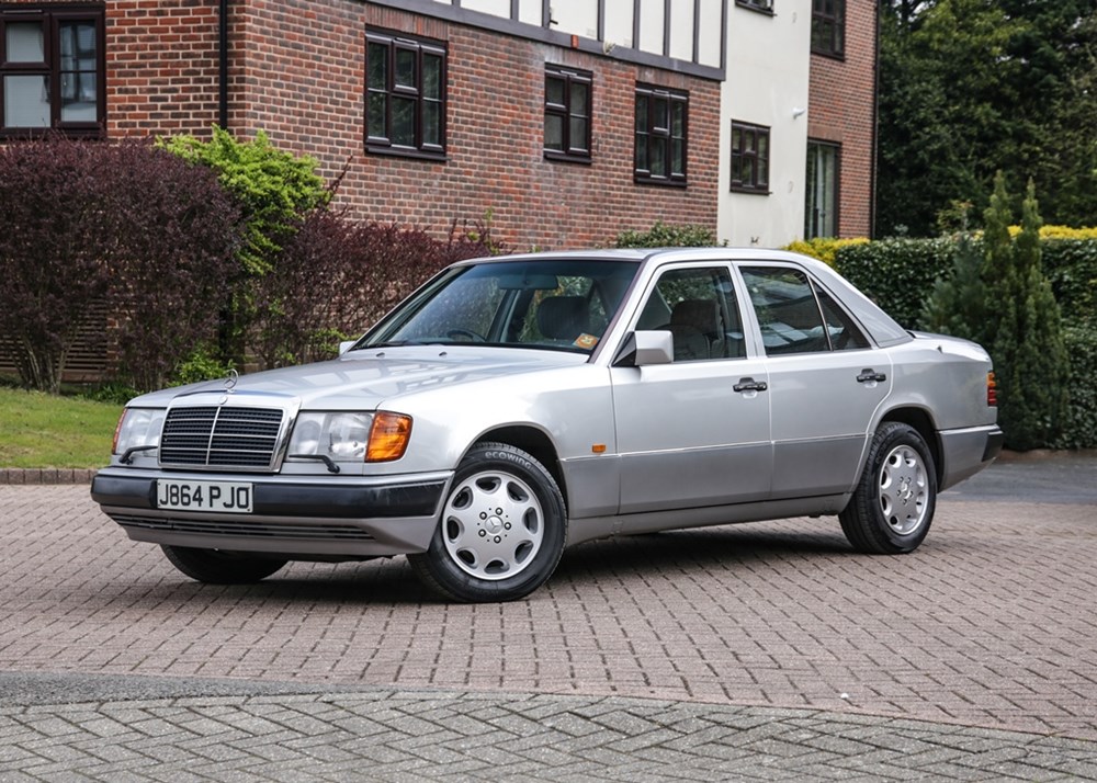 Silver classic Mercedes-Benz sedan parked in a suburban area, showcasing its vintage design.