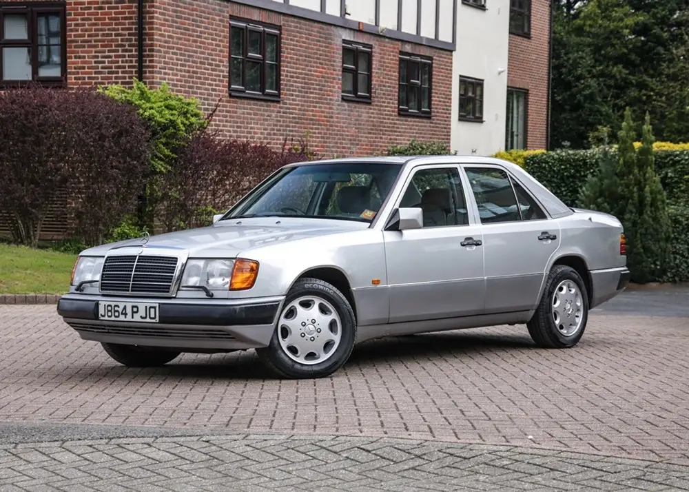 1992-mercedes-benz-260e-1jpganchorcenterampmodecropampwidth1000 - Engine Stories Silver classic Mercedes-Benz sedan parked in a suburban area, showcasing its vintage design.