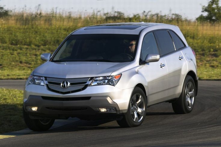 2007 Acura MDX - Engine Stories Silver SUV driving on a scenic road, showcasing sleek design and modern features. Ideal for family adventures and road trips.