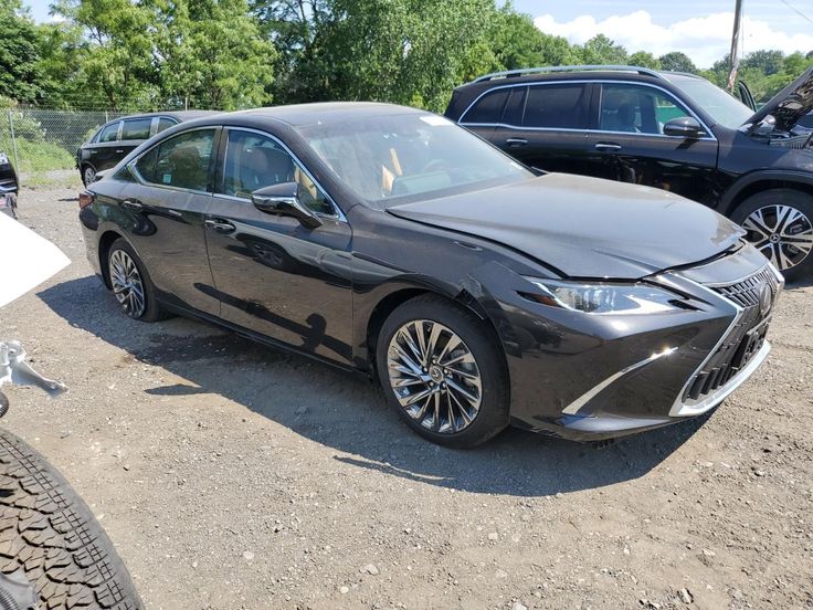 Black luxury sedan with front-end damage in a parking lot on a sunny day.