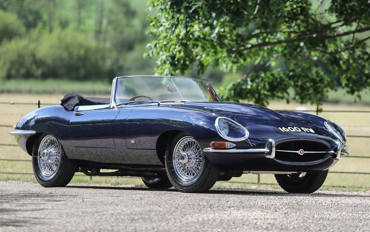 Classic blue convertible sports car parked outdoors, showcasing vintage elegance with wire wheels and sleek design.