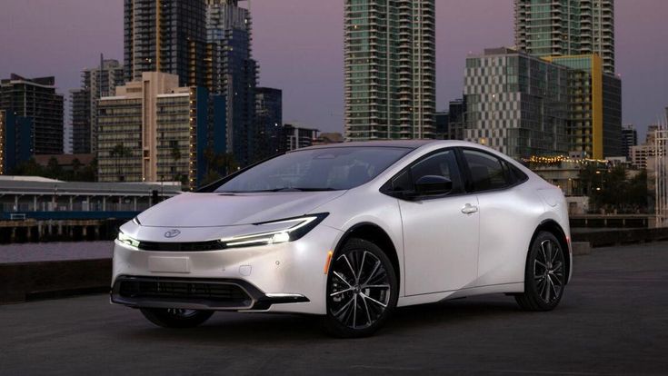 Sleek white car parked in an urban setting at dusk, with modern skyscrapers in the background. Ideal for city and auto enthusiasts.