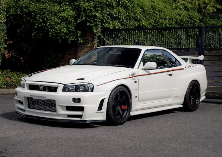 White Nissan Skyline GT-R R34 with sporty design, parked outdoors, showcasing iconic styling and performance.