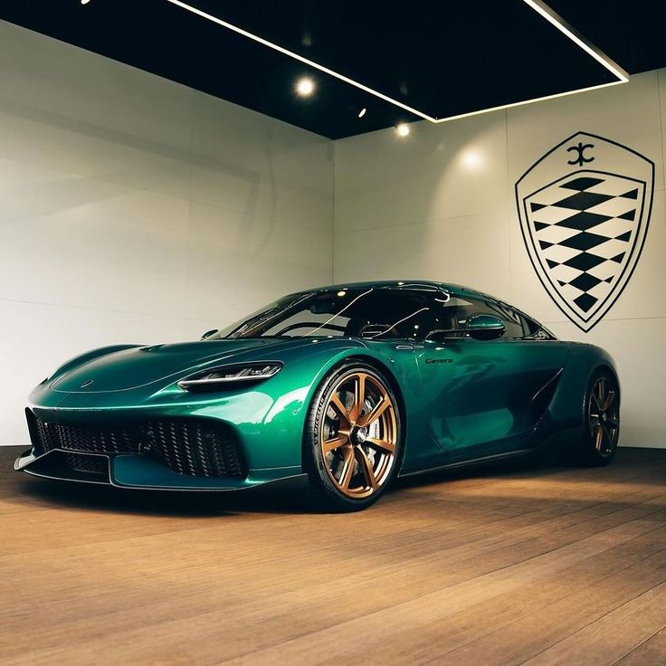 Sleek green luxury sports car in a showroom with stylish gold rims and modern design, under bright showroom lights.