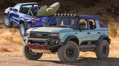 Two customized off-road SUVs in a desert landscape, showcasing rugged designs and surfboards on the rear.