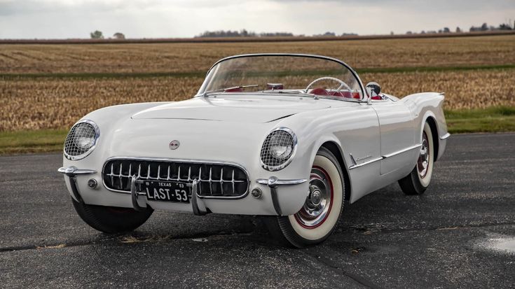 Vintage white convertible car parked on a rural road with a scenic field backdrop. Classic design evokes nostalgia and style.