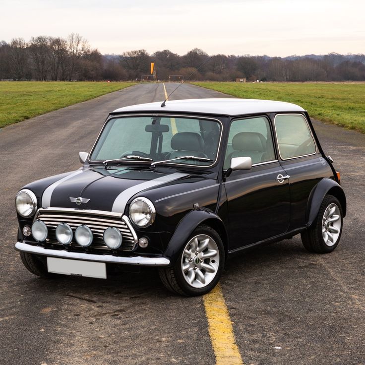 Classic black Mini Cooper parked on a scenic open road, showcasing its timeless design and iconic features.