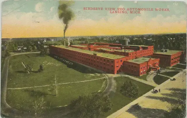 Historic aerial view of REO Automobile Works in Lansing, Michigan, showcasing industrial architecture and surrounding greenery.