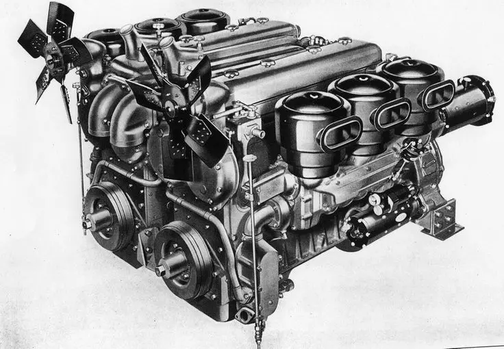 Vintage inline-six engine with dual fans and carburetors, showcasing intricate mechanical design. Perfect for classic car enthusiasts.