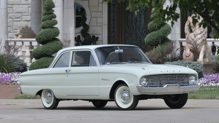 Ford Falcon 1960 - Engine Stories Classic white vintage car parked in front of a stylish mansion with manicured shrubs and elegant entrance.
