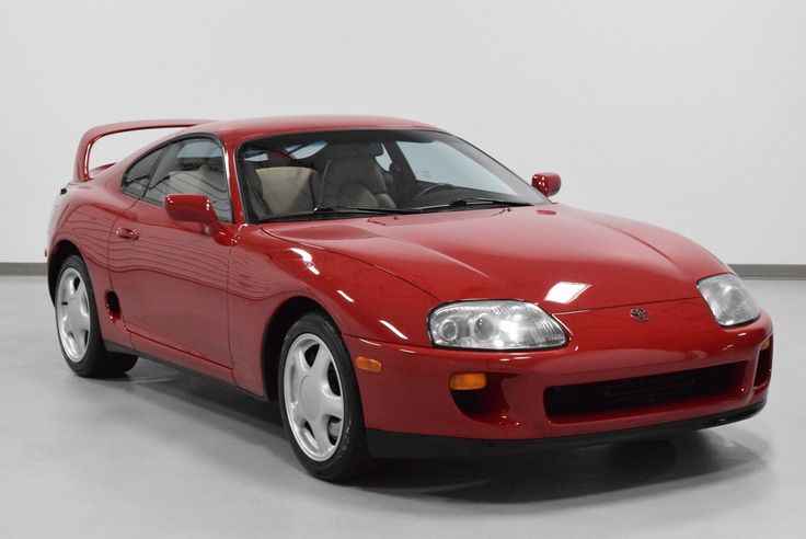 Red Toyota Supra MK4 sports car with sleek design in a showroom setting.