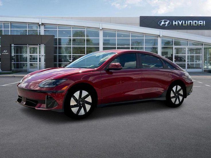 Red Hyundai electric car parked in front of dealership, showcasing sleek design and modern technology.