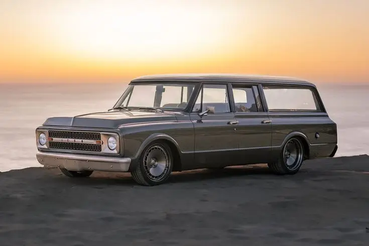 Icon Reformer 1970 Chevrolet Suburban SUV - Engine Stories Vintage car parked by the beach at sunset, capturing classic automotive design against a glowing skyline.