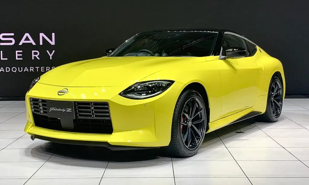 Nissan_FAIRLADY_Z_Z34_Version_ST_2022_left-front - Engine Stories Yellow Nissan sports car on display at a showroom, showcasing sleek design and modern features.