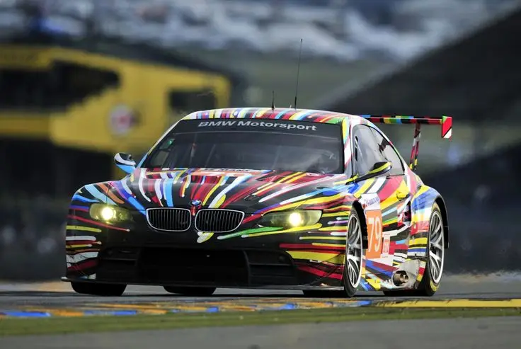 Vibrantly painted BMW race car speeding on track, showcasing dynamic design and sporty performance at a motorsport event.