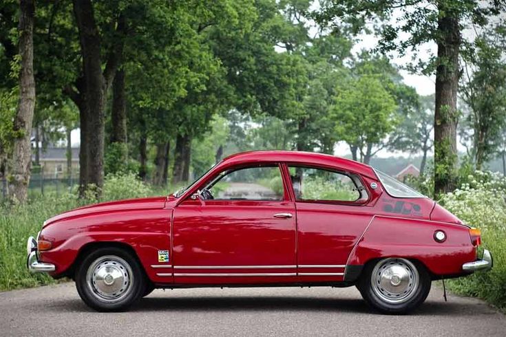 Classic red car parked on a scenic road, surrounded by lush green trees, showcasing vintage charm and automotive nostalgia.