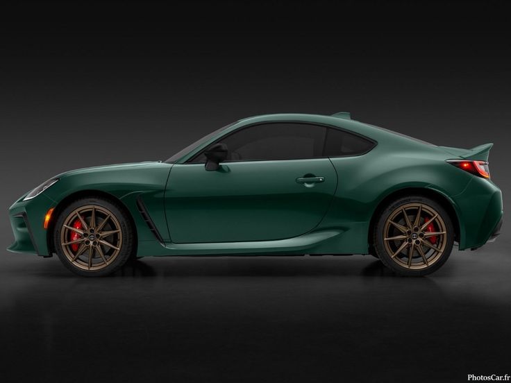 Green sports car with sleek design, bronze wheels, and aerodynamic profile, photographed in a studio setting.