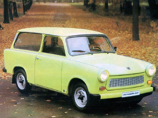 Trabant 601 Universal 1990_ - Engine Stories Vintage green Trabant car on a leaf-covered road in autumn, showcasing classic design and retro charm.