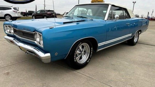 Classic blue convertible car parked at a dealership, showcasing vintage style and sleek design.