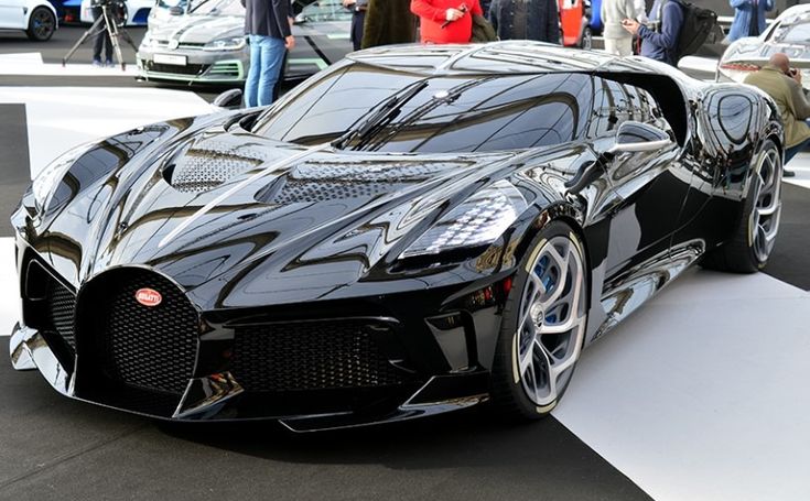 Sleek black luxury sports car on display at an automotive show, showcasing modern design and high-performance features.