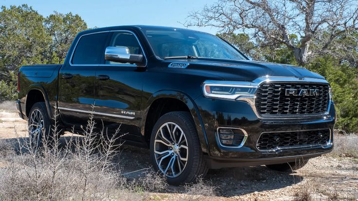 Black Ram 1500 truck parked outdoors, showcasing its sleek design and rugged features with trees in the background.