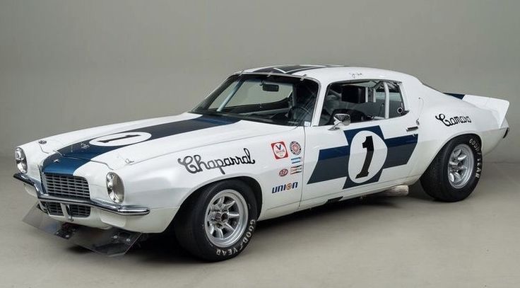 ff068491b1d1816b0f95fb1e98675019 - Engine Stories Vintage race car in white with blue stripes and the number 1. Featuring Chaparral branding and classic design.