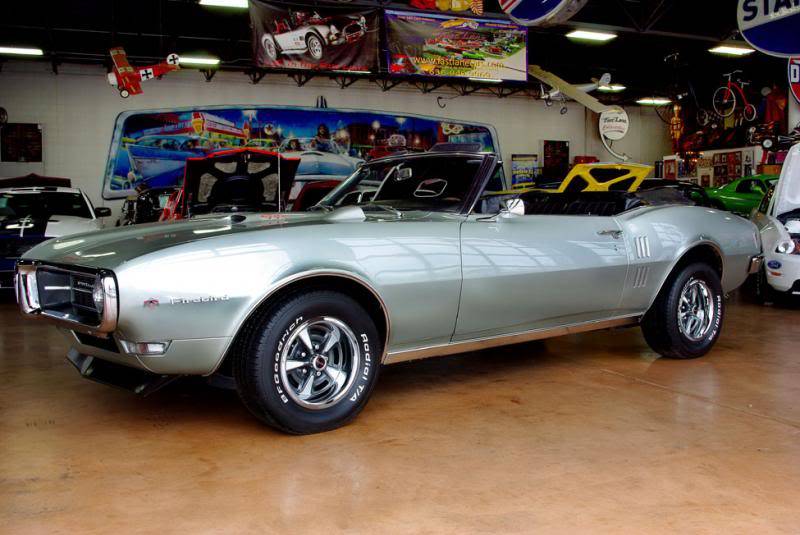 ford Project Phoenix 1968 - Engine Stories Classic silver convertible vintage car displayed in a showroom with colorful automotive decor.