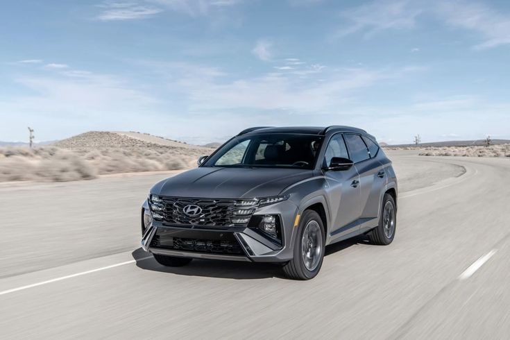 Sleek Hyundai SUV driving on a curved desert road under a clear blue sky, showcasing its modern design and advanced features.