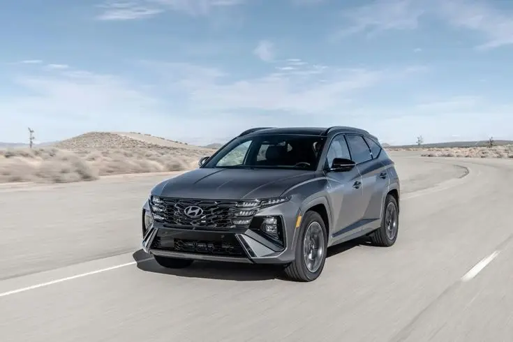 hyundai tucson 2025 - Engine Stories Sleek Hyundai SUV driving on a curved desert road under a clear blue sky, showcasing its modern design and advanced features.