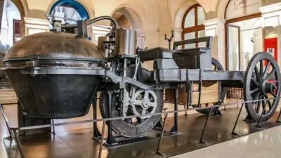Historic 18th-century steam-powered vehicle on display in a museum, showcasing early automotive engineering innovations.