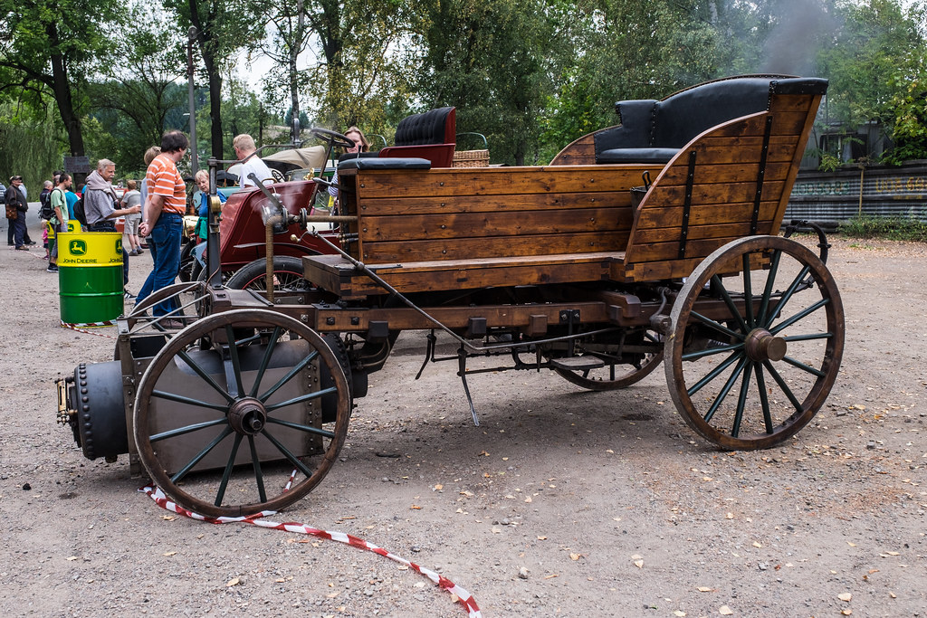 jozef bozeks 1815 - Engine Stories Vintage wooden steam car on display at an outdoor event, surrounded by people and trees in the background.