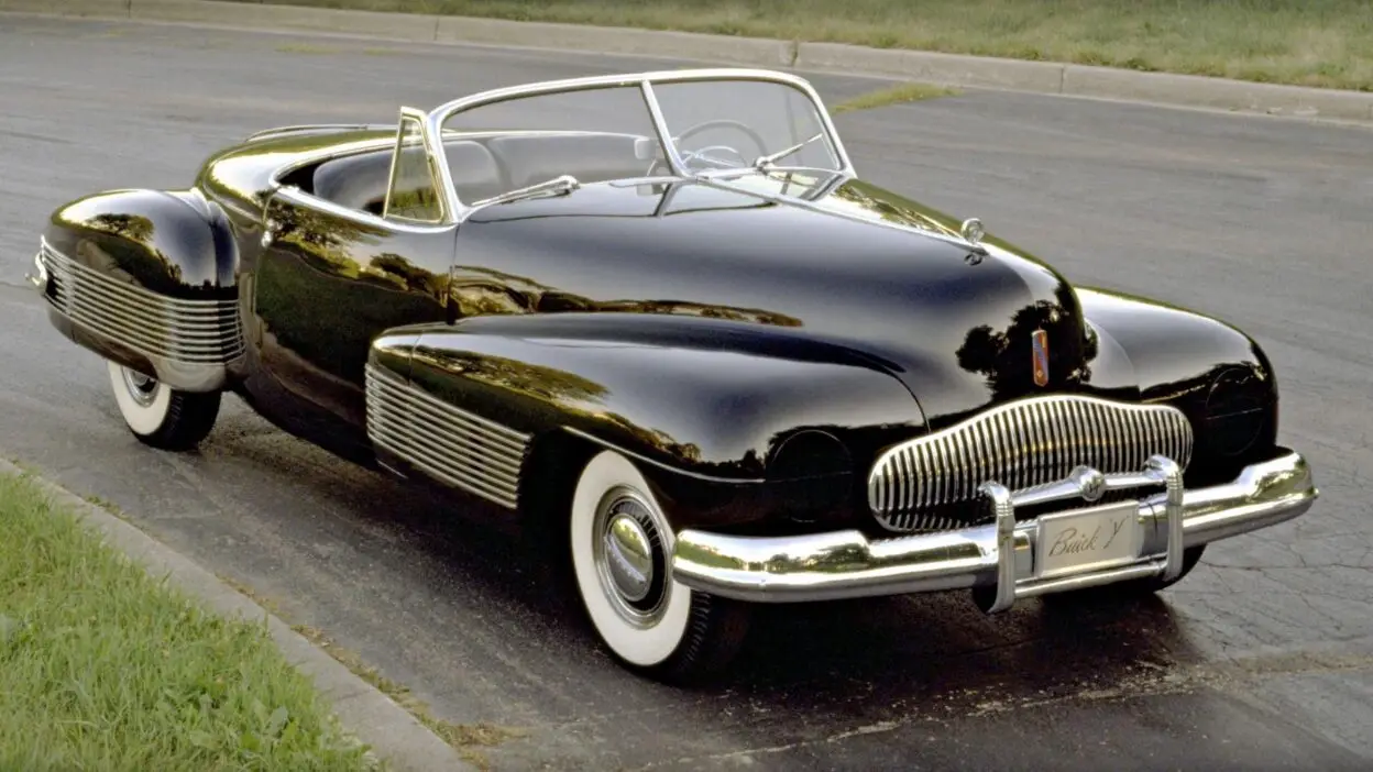 Sleek black classic convertible with chrome details parked on a road, showcasing vintage automotive design and style.